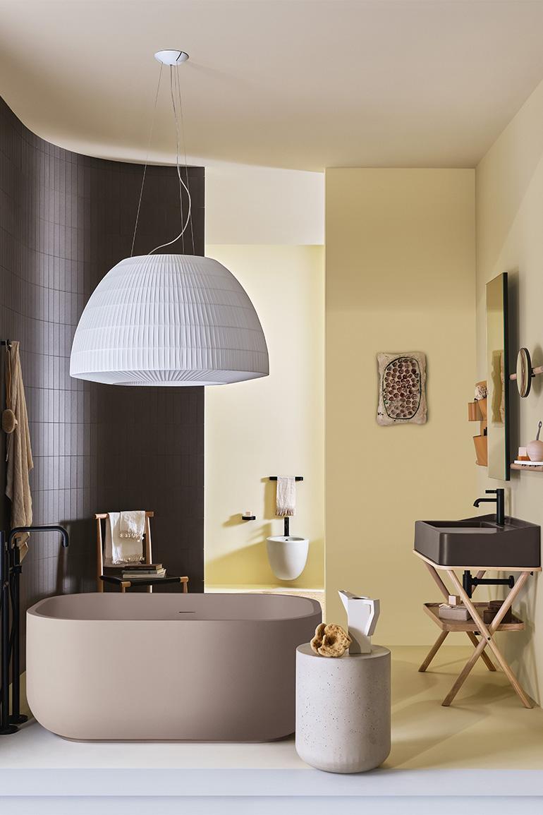 In this image, Siwa by Ceramica CIELO, designed by Andrea Parisio and Giuseppe Pezzano, the cabinet with ceramic washbasin in the Fango finish of the “Terre di Cielo” colour range combined with a tray and wooden structure in the Natural Oak finish. On the wall a Siwa mirror in the rectangular version, with wooden structure in the Natural Oak finish and a storage bag in natural leather. The composition is completed by the Dafne bathtub in LivingTec in the Arenaria finish of the “Terre di Cielo” colour range,